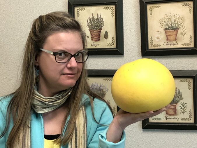 Author holds a fruit that's larger than her head